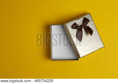 Golden Gift Box Open Lies On A Yellow Background, A Small Empty Gift