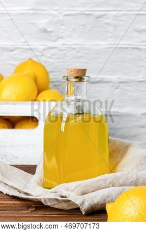 Lemon Syrup In Glass Bottle And Fruits In The Crate On The Background. Side View Of Fresh Citrus And