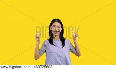 Young Asian woman making two thumbs up gesture showing joy and fun, Symbol of good friendship, Popul