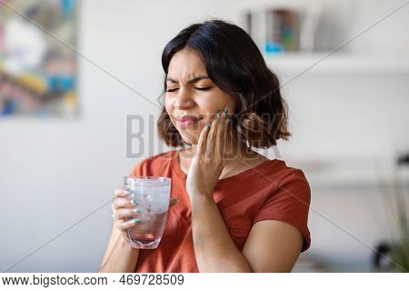 Sensitive Teeth. Young Arab Woman Drinking Water With Ice And Touching Cheek