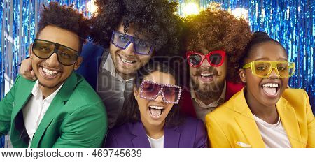 Happy Cheerful Multiracial People In Colorful Suits, Disco Glasses And Funny Wigs In Photo Booth