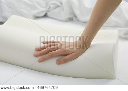 Woman Touching Orthopedic Memory Foam Pillow On Bed, Closeup. Space For Text