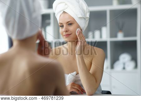 Young Woman Sits In The Bathroom In Front Of The Makeup Mirror And Does Cosmetic Procedures. Beautif