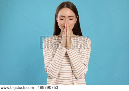 Woman With Clasped Hands Praying On Turquoise Background
