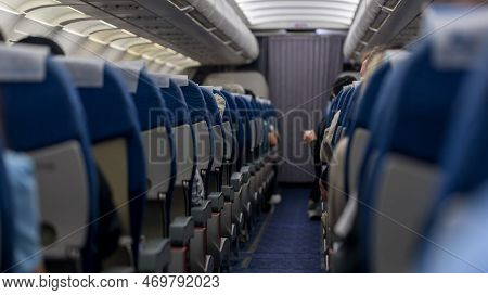 Passenger Seat. Interior Of Airplane With Passengers Sitting On Seats. Plane Cabin. The Interior Of 
