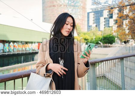 Serious Asian Business Young Woman Watiching In The Cell Phone App A Message Text, Outdoors. Unhappy