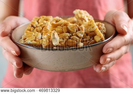 Woman Holding Bowl With Delicious Peanut Kozinaki Bars, Closeup