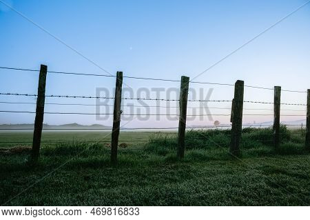 Blue Hour New Zealand Rural Sunrise Landscape Through Fence.