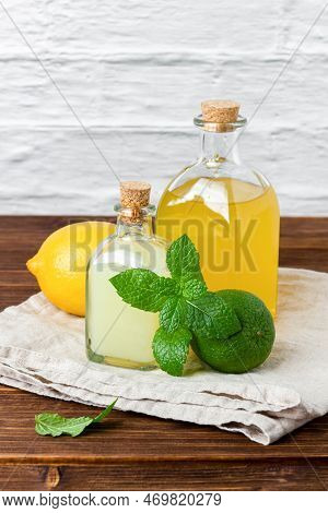 Lime And Lemon Syrups In A Glass Bottle With Fruits And Mint. Side View Of Fresh Citrus And Handmade