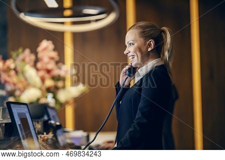Profile Of A Happy Receptionist Answering Calls At Hotel Reception.
