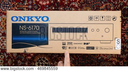 Paris, France - Dec 13, 2022: Pov Male Hand Pointing To Cardboard Package Of New Onkyo Ns-6170 Netwo