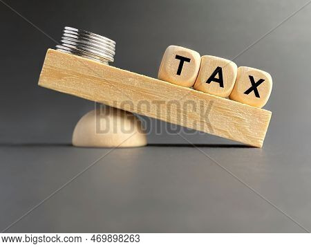 Tax Text On Wooden Blocks Background. Imbalance Between Income And Tax Payment Concept. Stock Photo.