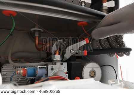 Man Repairing Gas Boiler With Waterpump Plier, Closeup