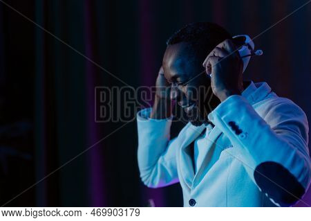 Portrait Of A Smiling Man In Headphones. Listening To Music. A Man In A White Jacket And Trousers.