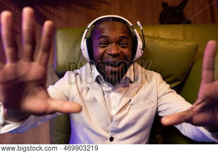 A Black Man Is Lying On The Sofa And Listening To Music. A Man In A White Suit Is Lying On A Green S