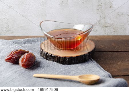 Natural Organic Healthy Date Syrup In A Glass Bowl With Whole Dates And Wood Spoon On The Background