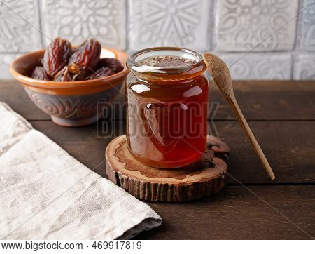 Natural Organic Healthy Date Syrup In A Glass Jar With Whole Dates And Wood Spoon On The Background