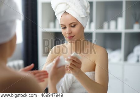 Young Woman Sits In The Bathroom In Front Of The Makeup Mirror And Does Cosmetic Procedures. Beautif