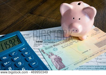 Tax Refund Check With Pink Piggy Bank And Calculator