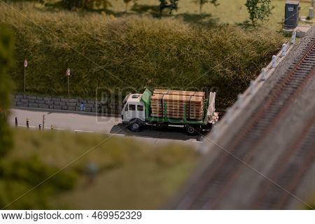 A Cargo Toy Car Carries Wooden Planks Under The Bridge Against The Background Of The Natural Landsca