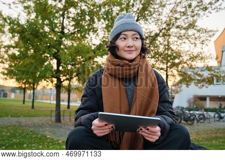 Smiling Young Girl, Korean Student Sits In Park In Scarf And Hat On Chilly Day, Draws Outdoors On Di