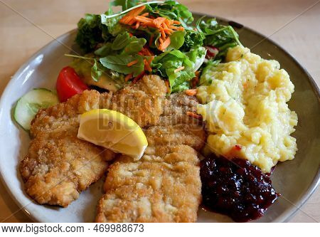 Two Wiener Schnitzels On A Plate With Sallat And Mashed Potatoes.