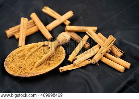 Dried Cinnamon Sticks And Powder On Olive Wood