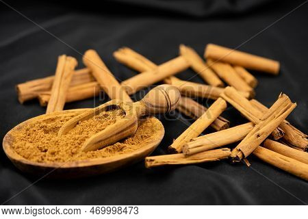 Dried Cinnamon Sticks And Powder On Olive Wood
