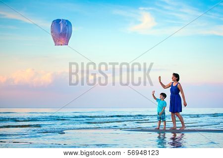 Young mother and son flying fire lantern together