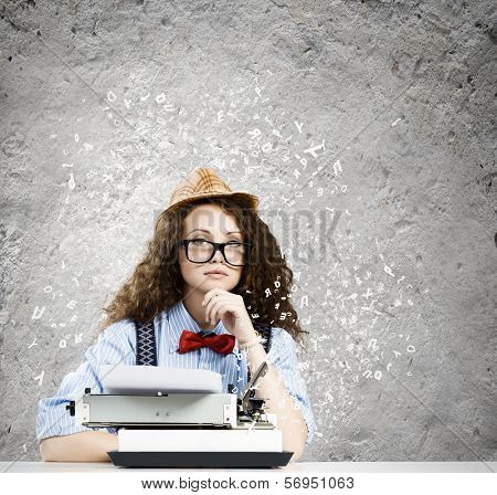 Young funny woman in glasses using typewriter