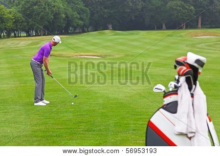A golfer addressing the ball on a par 4 fairway, series of 3. Focus is on the golfer.
