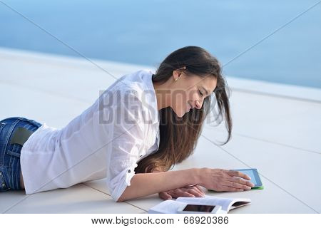 beautiful young woman relax and work on laptop computer while listening music on heaphones and read book at home