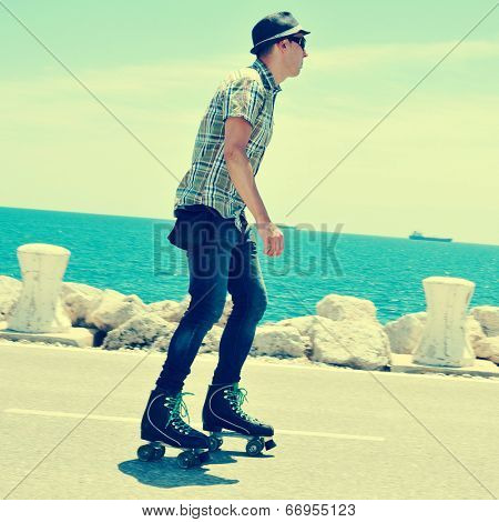 a young man roller skating near the sea, with a cross-processed effect