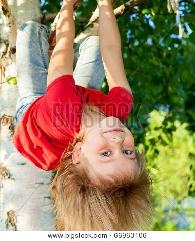 Little girl having fun playing on birch tree