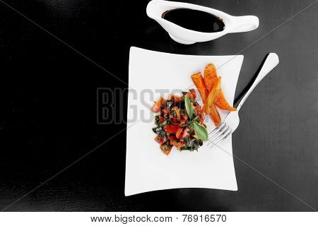 vegetable salad : cherry tomatoes and basil with sweet baked potato served on white plate with sauceboat full blask soy sauce on wood
