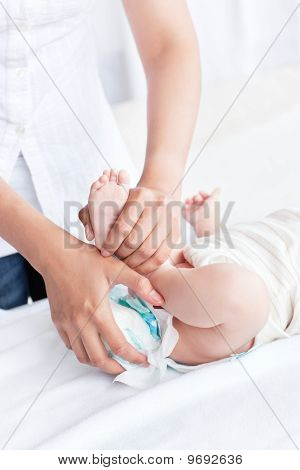 Primo piano di una madre attenta che toglie il pannolino sporco del suo bambino sdraiato In camera da letto