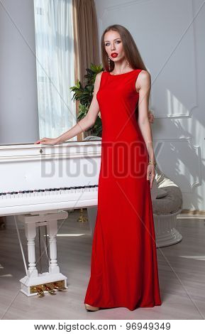 Beautiful brunette woman in a red dress. Studio shot. Long hair. Red lips.