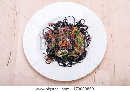 Black spaghetti with seafood and vegetables .