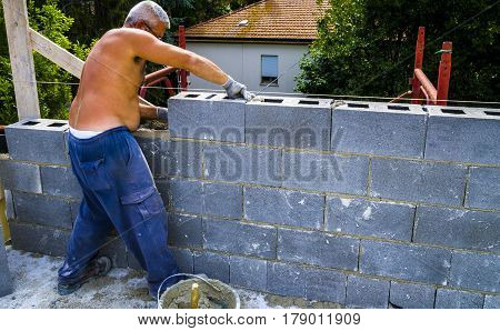 construction worker bricklayer installing red brick with trowel putty knife outdoors