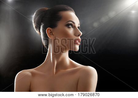 Fresh beauty. Stunning beautiful young woman with perfect skin and healthy hair in a bun posing sensually looking away on black background lens flare copyspace beauty perfection cosmetic treatment