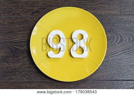 The number ninety-eight on the plate yellow and brown background.