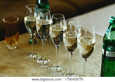 Glasses with champagne stand in a ray on the table