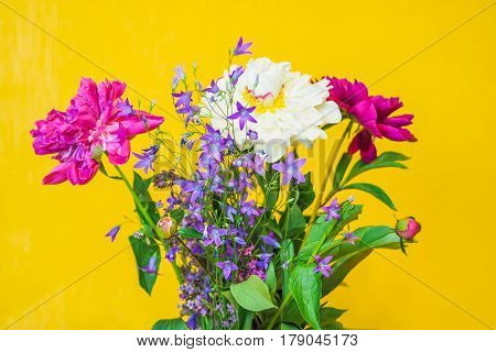 Beautiful white and purple peonies bouquet on the blurred yellow background