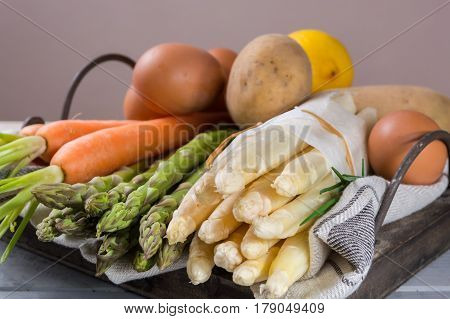 Ingredienrs for seasonal spring tasty vegetarian dinner - fresh white and green asparagus carrot potato and chicken eggs ready to cook.