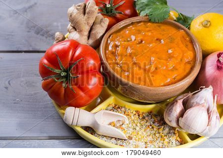 Bowl of vegetable Tikka Masala sauce and ingredients that go into making it - red tomatoes chili pepper carrot coriander leaves onion garlic gember. Used widely in Indian food.