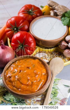 Bowl of vegetable Tikka Masala sauce and ingredients that go into making it - red tomatoes chili pepper carrot coriander leaves onion garlic gember. Used widely in Indian food.