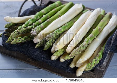 Fresh spring green and white asparagus ready to cook on wooden backgroung close up