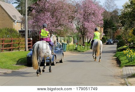 Fulwell Road Finmere Oxfordshire United Kingdom March 26 2017: Female riders and horses on village road wearing Please Pass Wide & Slow sign on fluorescent jacket Oxfordshire UK