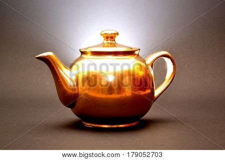 golden teapot shines on a dark background