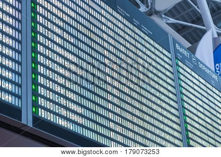 Closeup of blue departure board with destinations and times timetable in airport abstract background